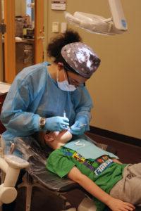 牙科卫生专业的学生在诊所检查一个男孩的口腔.